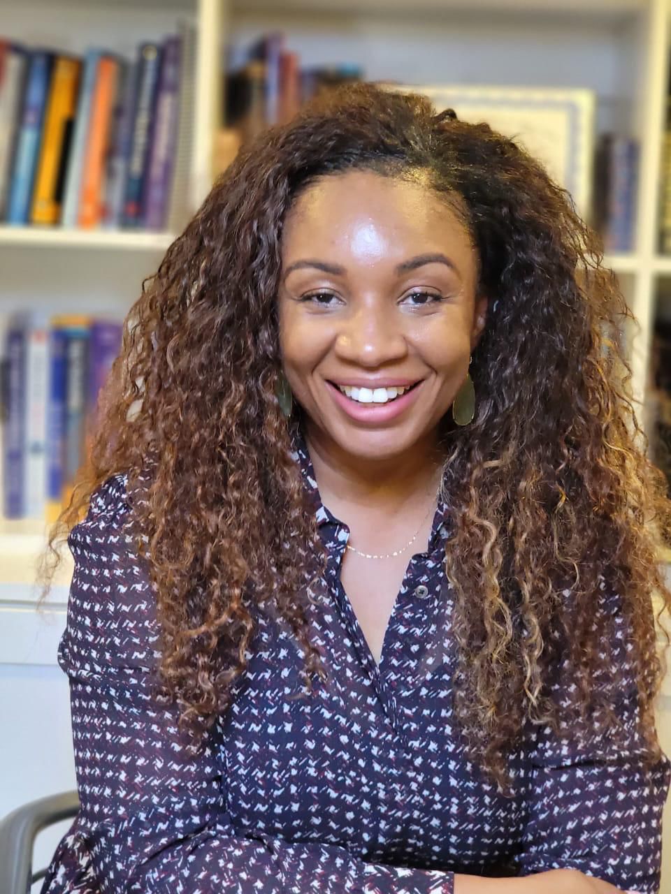 Chika Odioemene smiling in front of a bookshelf
